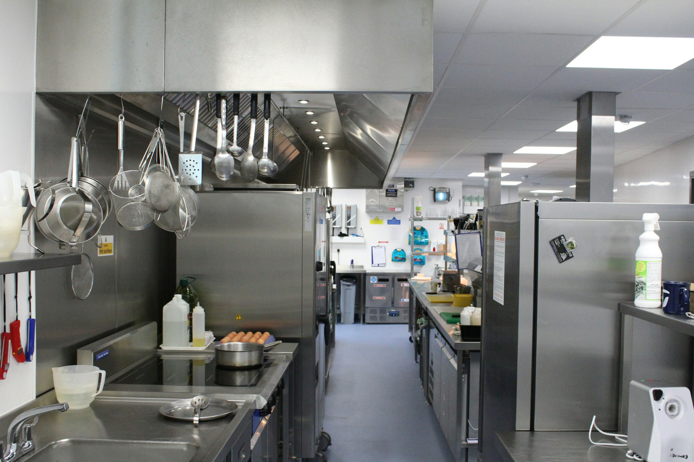 A commercial kitchen with stainless steel equipment and hanging cookware